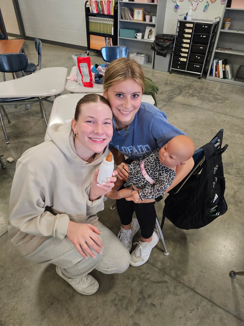 20240926_091214-min two girls in classroom caring for baby doll