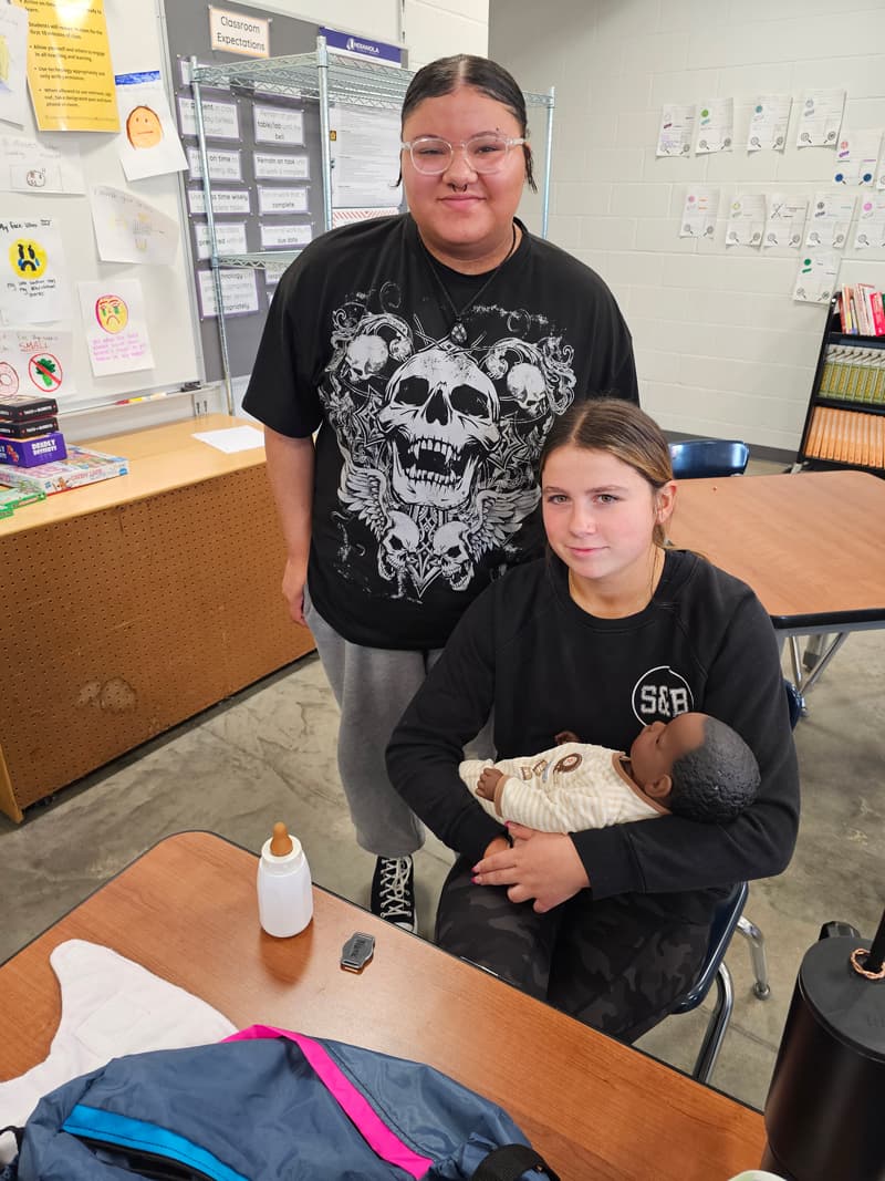 20240926_091230-min two girls in classroom caring for baby doll