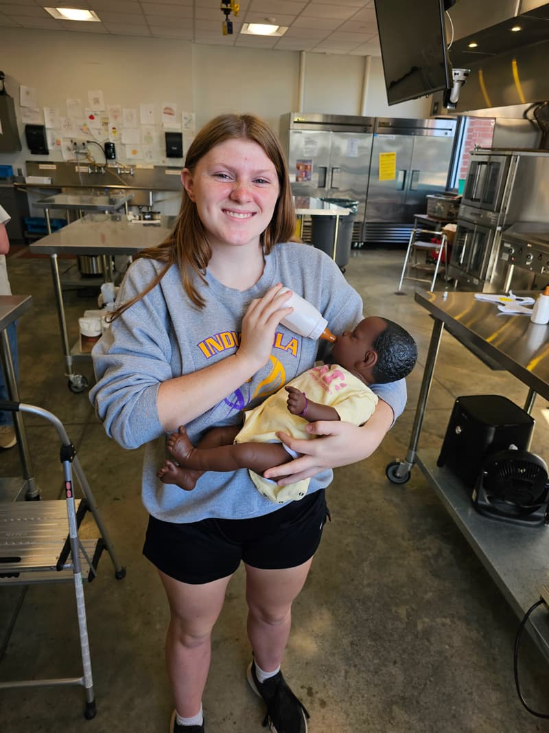 20240926_091301-min girl holding a bottle feeding baby doll