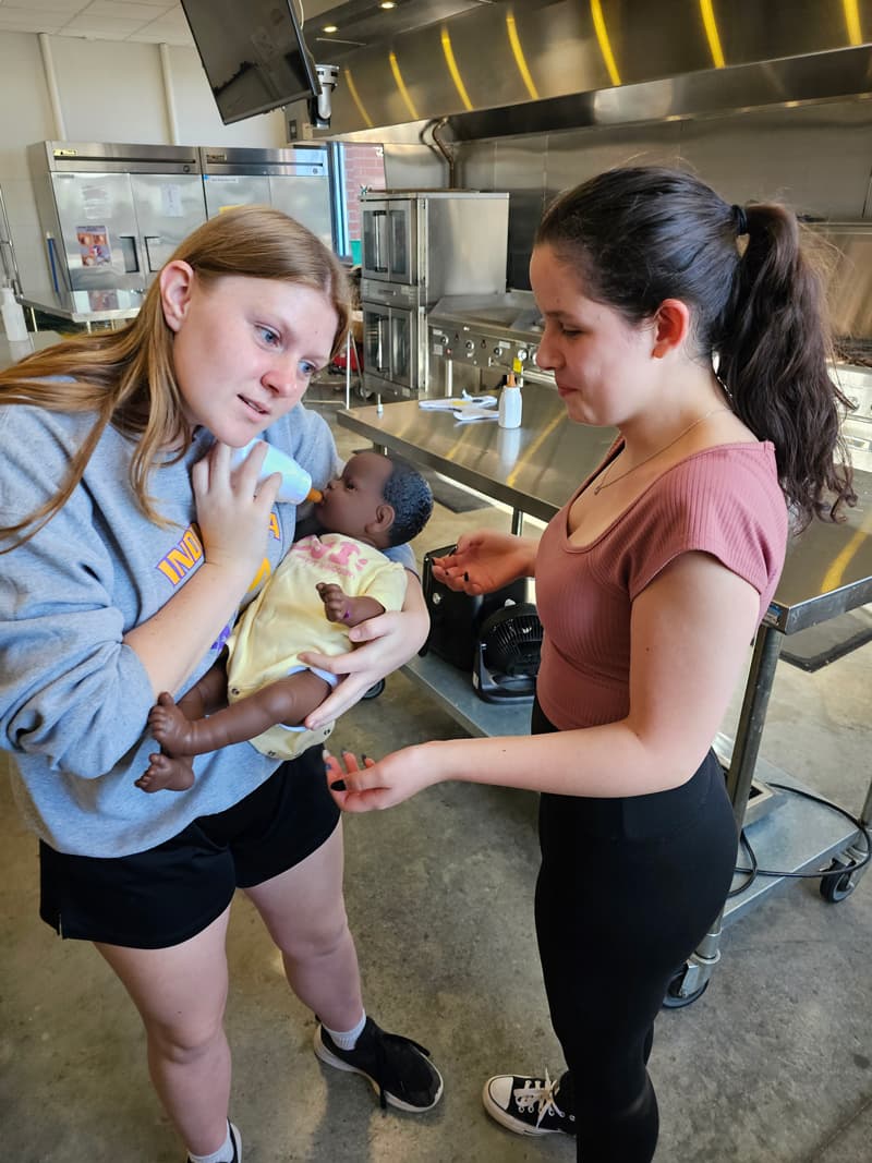 20240926_091308-min two girls taking care of a baby