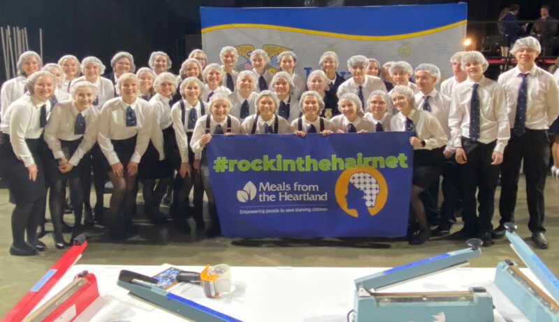 ICT-8 Group of people with hair nets on holding sign for meals from the heartland